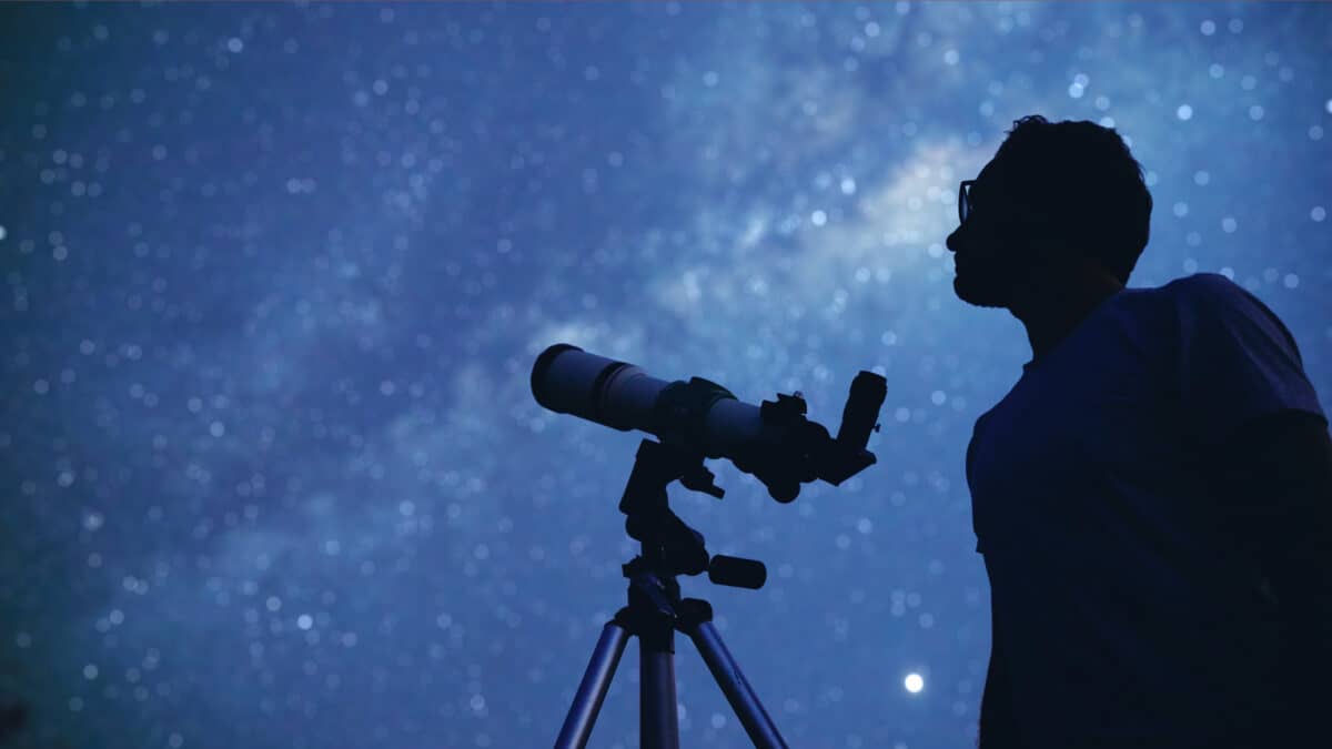 Astronomer with a telescope watching the stars and Moon.